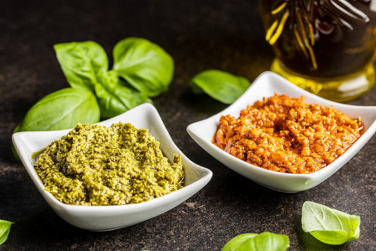 low carb Green basil and red tomato pesto dip sauce and basil leaves on